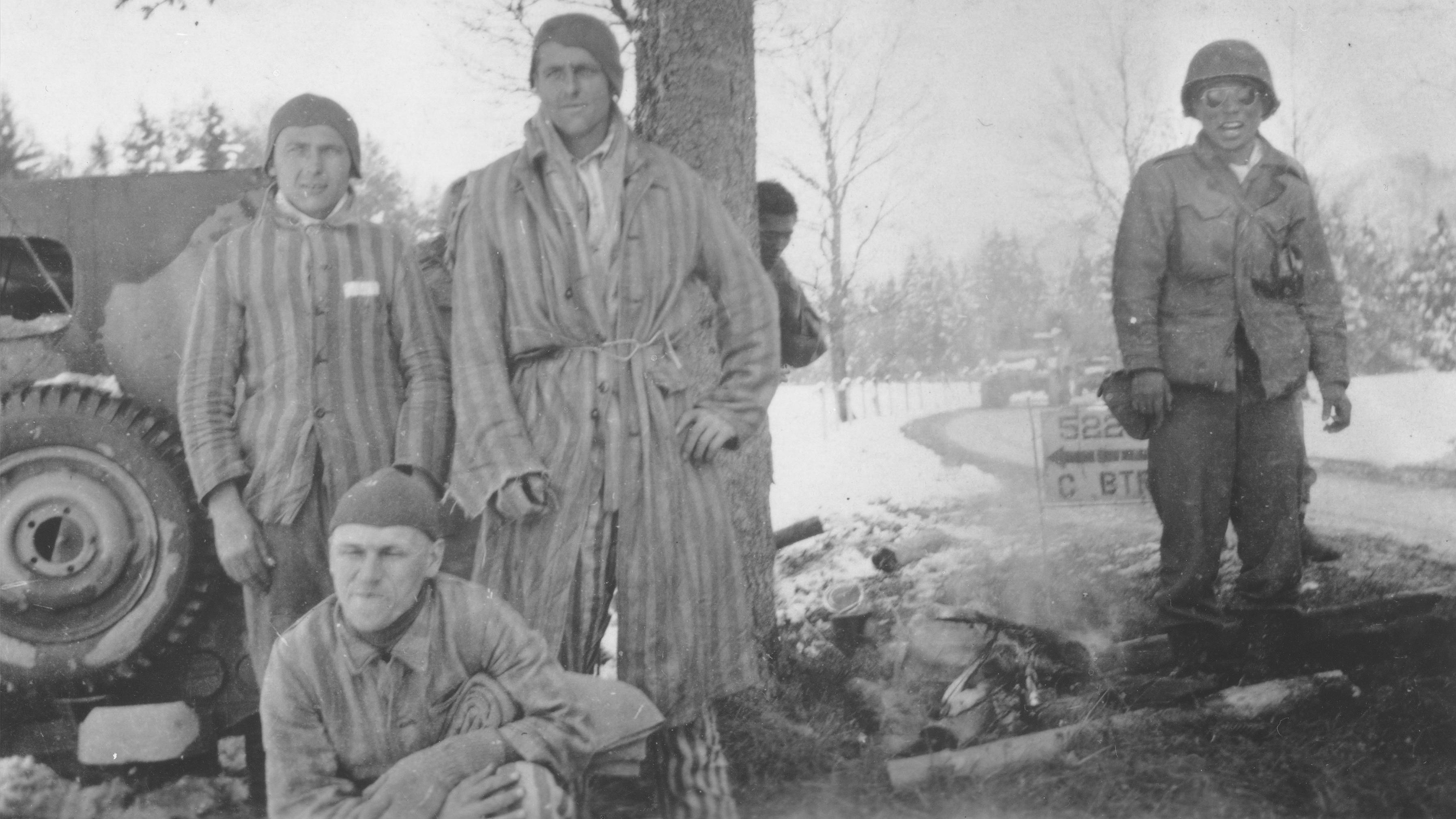 George Oiye (rechts), ein japanisch-amerikanischer Soldat des 522nd Field Artillery Battalion, bereitet ein Lagerfeuer für die von seiner Einheit befreiten KZ-Häftlinge in der Nähe von Waakirchen vor.